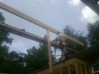 Carpenter setting a ridge beam over a new addition frame — Ice Dam Removal by Roofing Brothers in Pooler