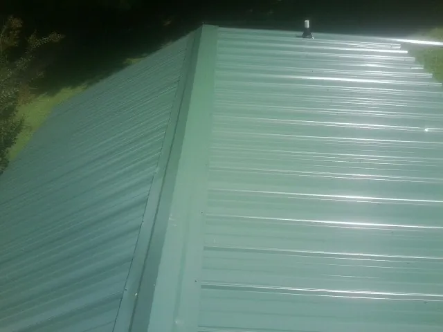 New green metal panels meeting at the ridge of a roof — Flat Roof Repair work by our crew in Pooler