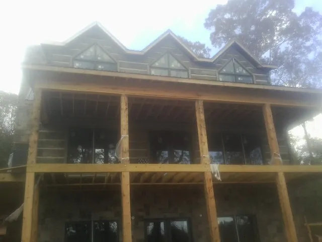 Dormers and porch framing on a large log home under construction — Roof Coating work by our crew in Pooler