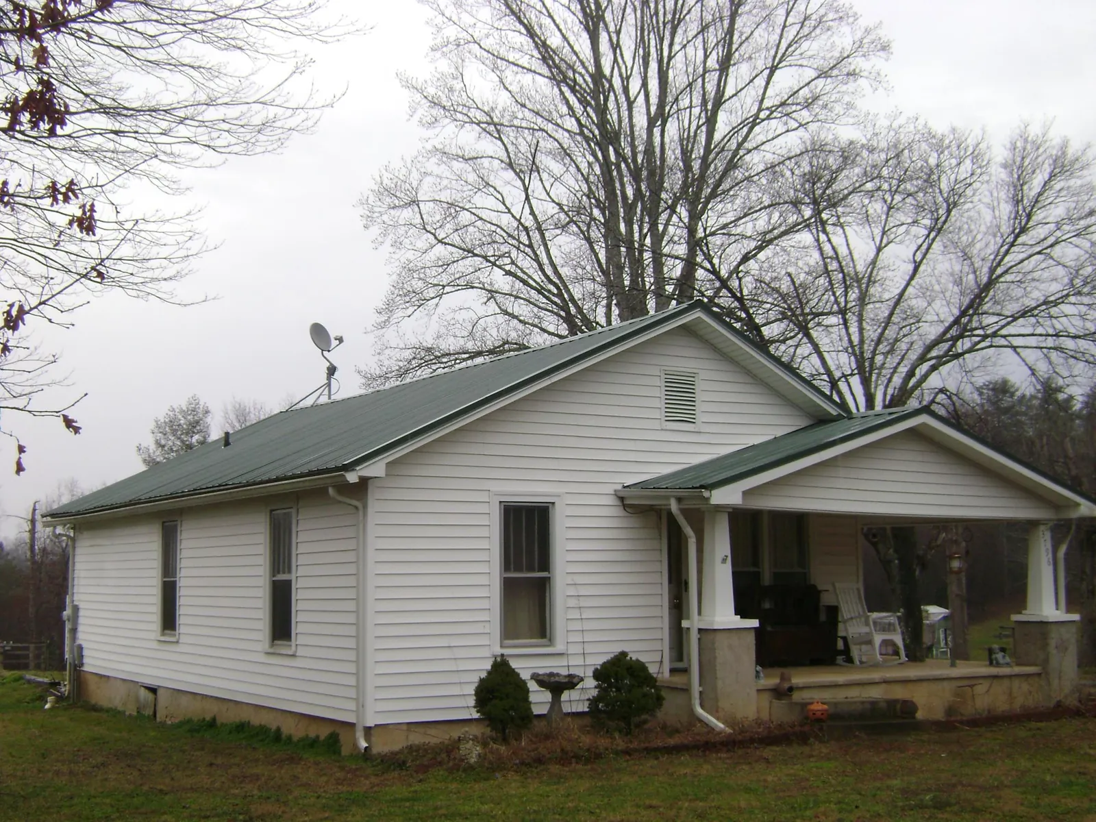 Green metal roof on a white bungalow with a side porch in Pooler