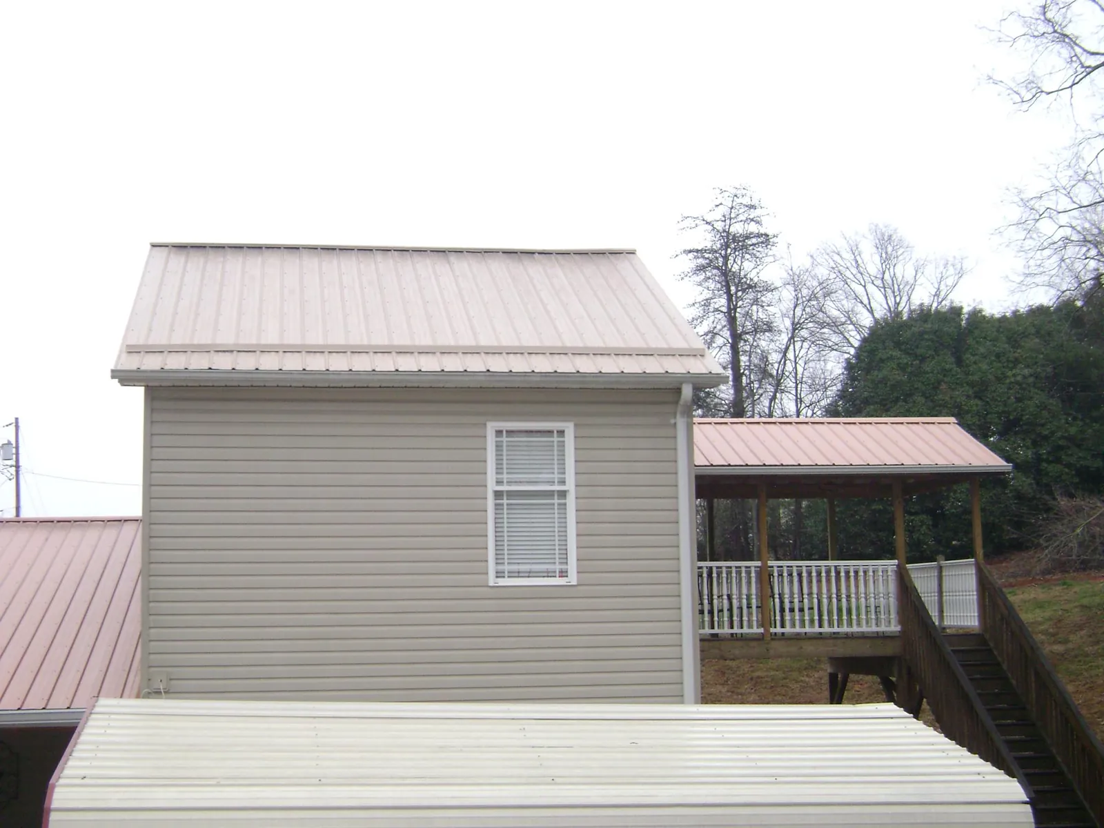 Tan metal roofs on a two story addition and attached porch, from a Roof Replacement job in Pooler